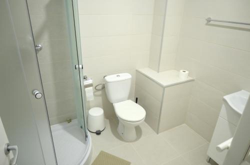 a white bathroom with a toilet and a shower at Luana Airport Apartments #6 in Otopeni