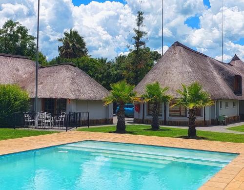 a resort with a swimming pool and two huts at Clivia Lodge in Vanderbijlpark