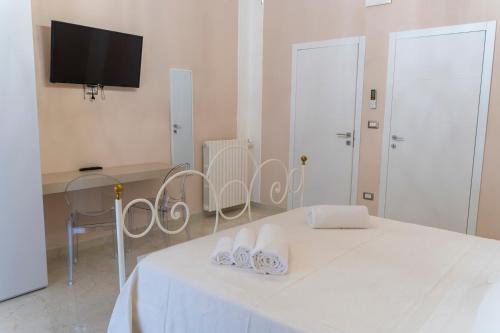 a white room with a bed and a table and a tv at A casa dei miei in San Pietro Vernotico