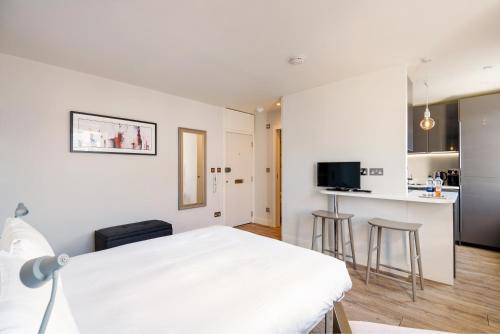 sypialnia z białym łóżkiem i kuchnią w obiekcie Brand new studio flat in the heart of Notting Hill w Londynie