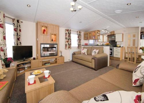 uma sala de estar com um sofá e uma televisão em Lakeside Holiday Park em Burnham on Sea