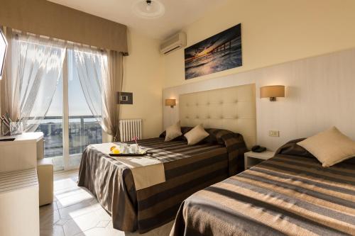 una camera d'albergo con due letti e una finestra di Hotel King a Marina di Pietrasanta