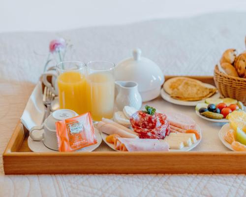 a tray of food with breakfast foods and orange juice at Hotel Le Grimaldi by Happyculture in Nice