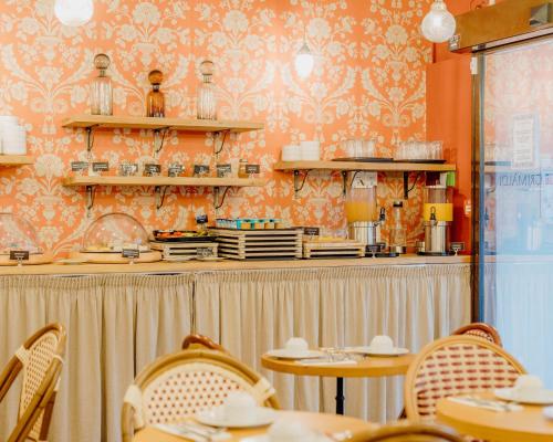 a restaurant with tables and chairs in a room at Hotel Le Grimaldi by Happyculture in Nice