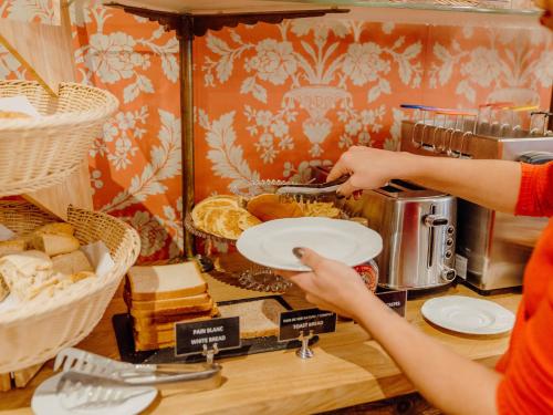 a person holding a plate of food in a bakery at Hotel Le Grimaldi by Happyculture in Nice