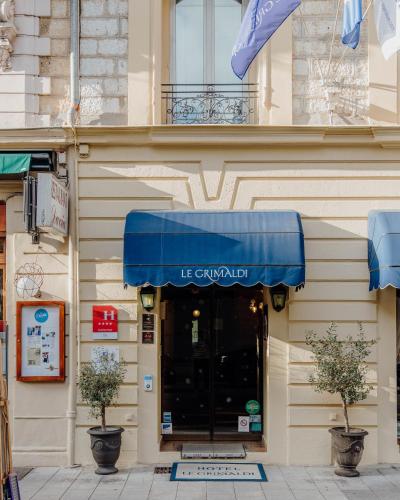 a building with a blue awning over a doorway at Hotel Le Grimaldi by Happyculture in Nice