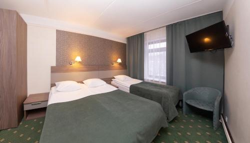a hotel room with two beds and a flat screen tv at Hotel St. Barbara in Tallinn