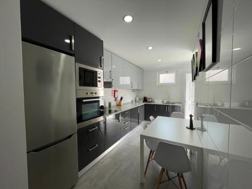 a kitchen with a refrigerator and a table with chairs at Happy House Barreiro in Barreiro
