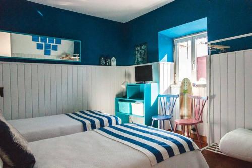 a bedroom with two beds and a blue wall at Casa da Ti´ Milia in Encarnação