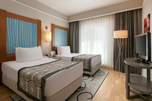 a hotel room with a bed and a desk and a television at Xanadu Island in Akyarlar
