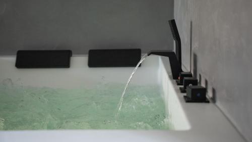 a bath tub with a stream of water in it at Ennéa - Jacuzzi & Luxury Suites in Perpignan