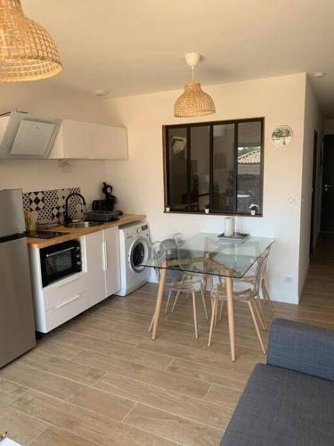 une cuisine avec une table en verre et une salle à manger dans l'établissement A 10min d'Hossegor, T2 avec jardinet et terrasse, à Tosse