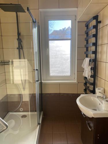 a bathroom with a shower and a sink and a window at Centrum No. 1 in Polanica-Zdrój