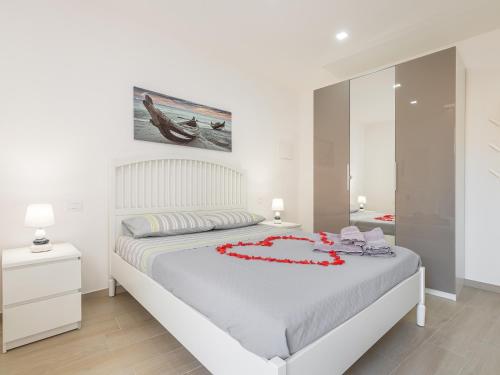 a white bedroom with a bed with red flowers on it at Sabamiglia Apartments in Cagliari