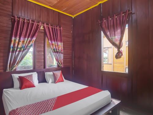 Un dormitorio con una cama con sábanas rojas y blancas y ventanas. en OYO 92225 Filadelfia Resto & Penginapan, en Manado