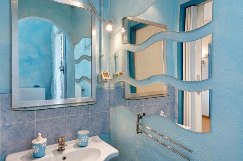 ein blaues Badezimmer mit einem Waschbecken und zwei Spiegeln in der Unterkunft Casa Cecilia in Marina dʼAndora