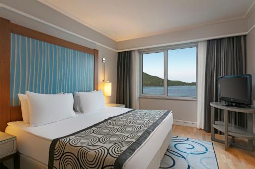 a hotel room with a large bed and a television at Xanadu Island in Akyarlar