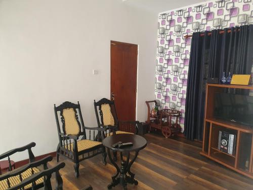 ein Wohnzimmer mit Stühlen, einem Tisch und einem TV in der Unterkunft Belihull Vila in Nuwara Eliya