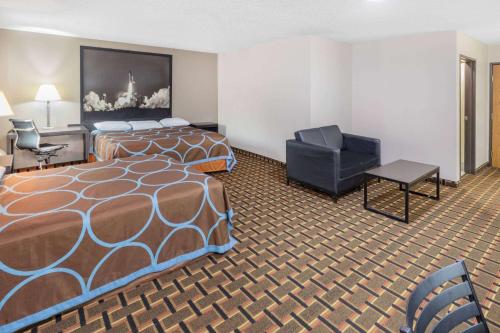 a hotel room with a bed and a chair at Super 8 by Wyndham League City Kemah Area in League City