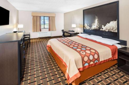 a hotel room with a bed and a flat screen tv at Super 8 by Wyndham League City Kemah Area in League City