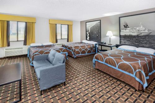 a hotel room with two beds and a chair at Super 8 by Wyndham League City Kemah Area in League City