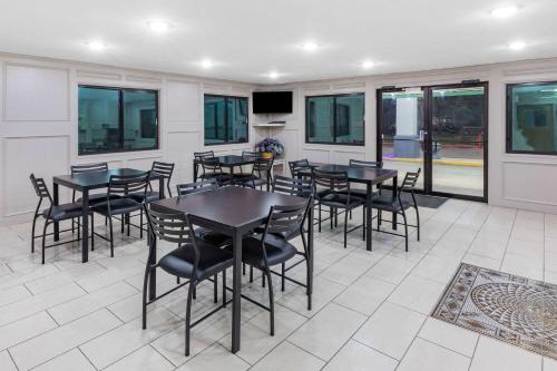 a dining room with tables and chairs and windows at Super 8 by Wyndham League City Kemah Area in League City