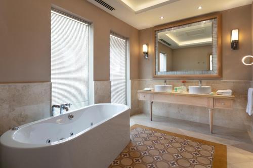 a bathroom with a tub and two sinks and a mirror at Xanadu Island in Akyarlar