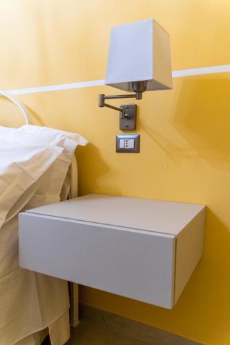 a white bedside table with a light on a wall at A casa dei miei in San Pietro Vernotico