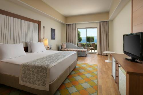 a hotel room with a bed and a flat screen tv at Xanadu Island in Akyarlar