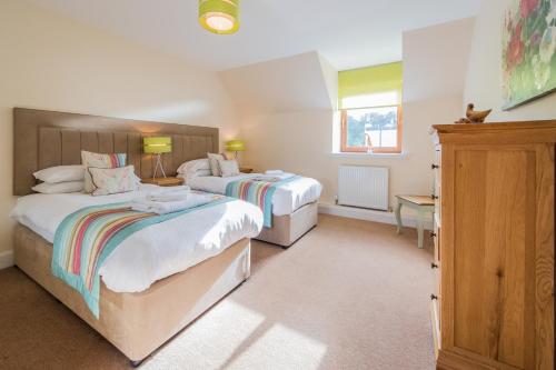 a bedroom with two beds and a desk and a window at The Granary with Hot Tub in Forgandenny
