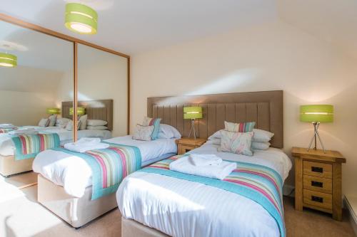 a bedroom with two beds and a large mirror at The Granary with Hot Tub in Forgandenny
