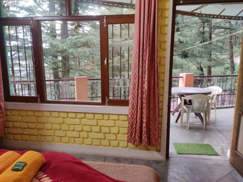 a room with a balcony with a table and windows at Shree Guest House in McLeod Ganj