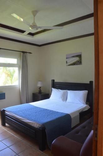 1 dormitorio con 1 cama y ventilador de techo en Butterfly Villas, en Grand'Anse Praslin