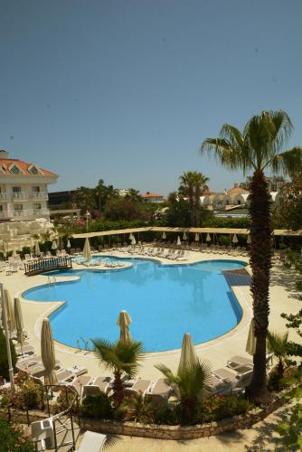 a large swimming pool with chairs and palm trees at MIRAMOR HOTEL & Spa - ULTRA ALL INCLUSIVE SELECTION in Kemer