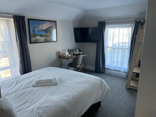 ニューキーにあるHotel Penwigの白いベッドとデスクが備わるホテルルームです。