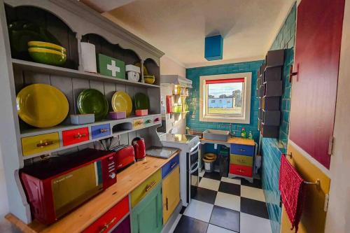 a kitchen with colorful cabinets and plates on the shelves at The Beach Hut in Scratby
