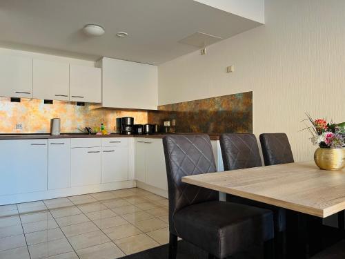 a kitchen with white cabinets and a wooden table and chairs at Familienapartment mit Panoramablick zur Frauenkirche in Dresden