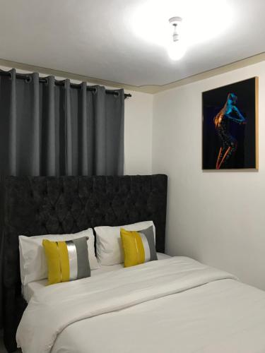 Un dormitorio con una cama grande con almohadas amarillas y blancas en Tawi Homes en Nairobi