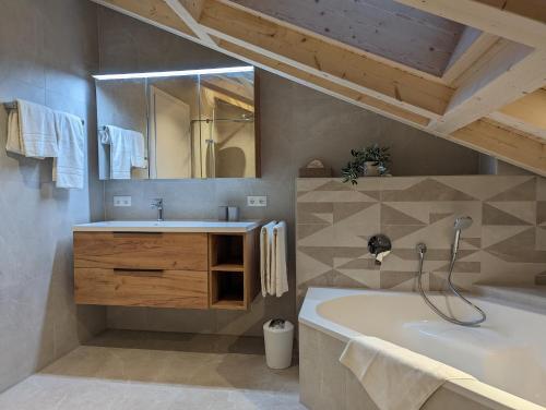 een badkamer met een bad, een wastafel en een spiegel bij ApartSchön in Schwangau