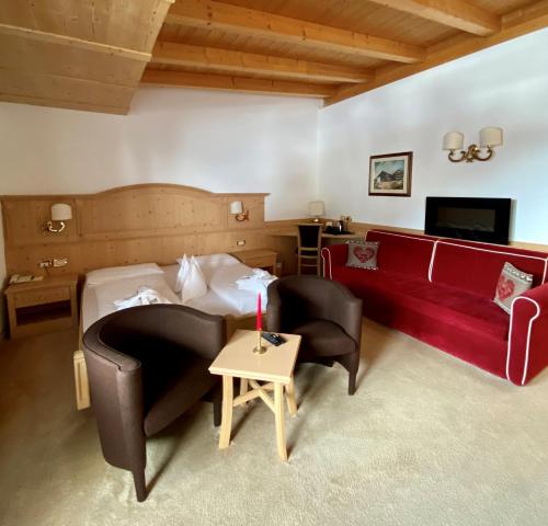 a hotel room with a bed and a couch and a table at Hotel Aaritz in Selva di Val Gardena