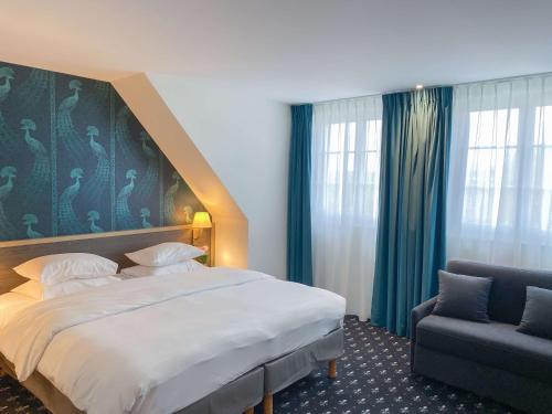 um quarto de hotel com uma cama grande e uma cadeira em Best Western Royal Hotel Caen em Caen