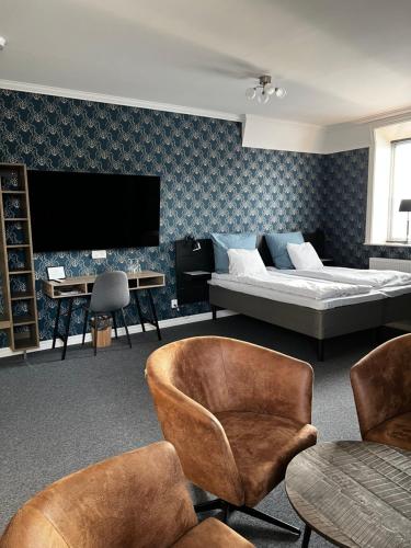 a living room with a bed and chairs and a tv at Norrfly Herrgård in Kilafors