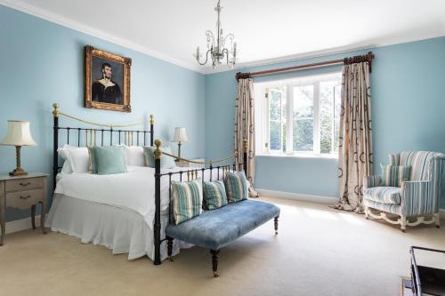 Schlafzimmer mit blauen Wänden, einem Bett und einem Stuhl in der Unterkunft The Casterton Grange Estate in Kirkby Lonsdale