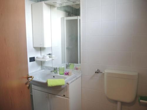 a bathroom with a sink and a toilet and a mirror at Apartment with garden in residence with pool in Bibione
