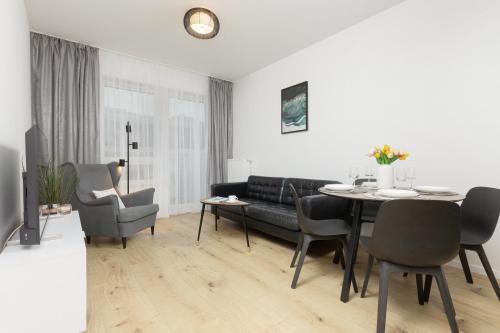 uma sala de estar com um sofá, uma mesa e cadeiras em Two-Bedroom Elegant Apartment with Parking Warsaw Praga by Renters em Varsóvia