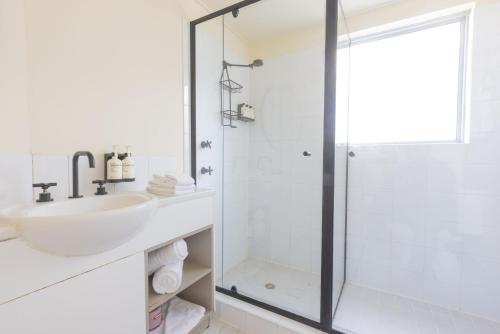 a white bathroom with a sink and a shower at Selina Brisbane in Brisbane