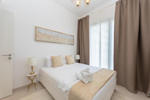 a white bedroom with a white teddy bear on a bed at Chic and Modern 1BR, Near Golf Course with Pool and Gym in Dubai
