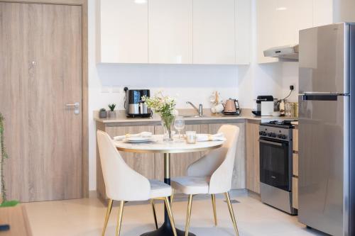 a kitchen with a table and chairs and a refrigerator at Chic and Modern 1BR, Near Golf Course with Pool and Gym in Dubai
