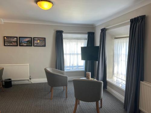 a living room with chairs and a table and windows at Hotel Penwig in New Quay