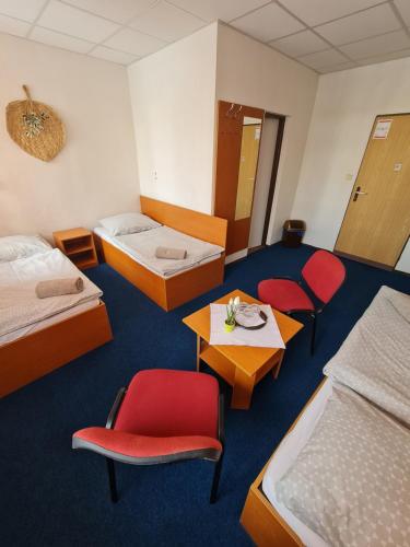Habitación de hotel con 2 camas, mesa y sillas en Penzion Olympia en Banská Bystrica